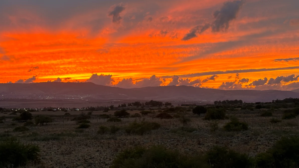Vivid orange sunset over a dark mountain ridge and open landscape