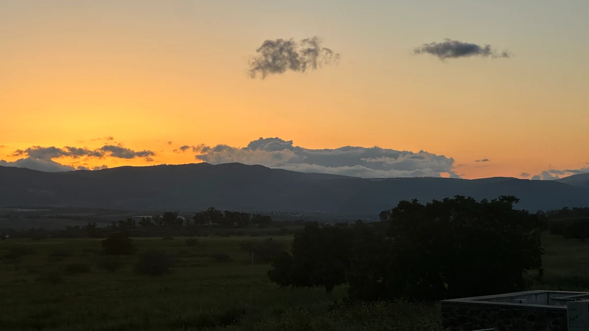 Golden evening sky and clouds above a silhouetted mountain ridge